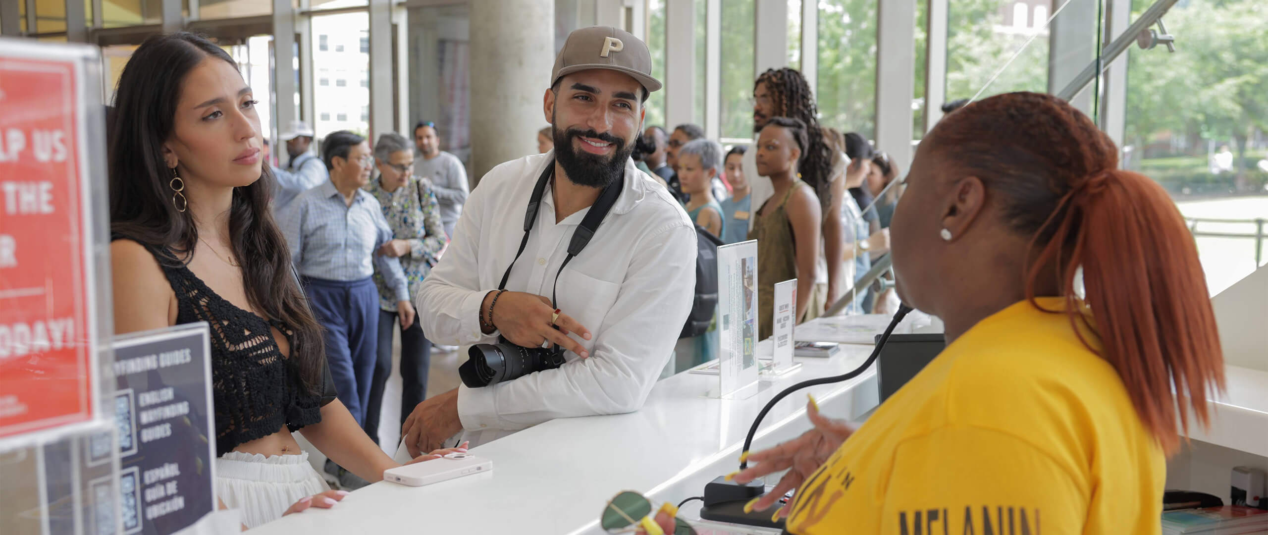 Woman and man at Visitor's Info Desk talking to museum staff.